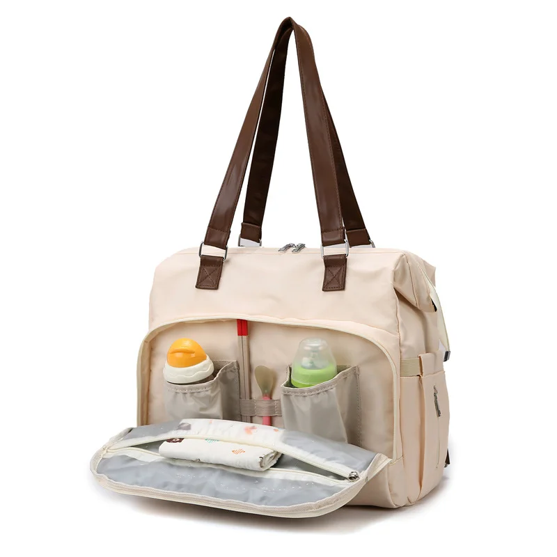 Guangzhou Fuliya Industry Co.,Ltd C-81133 Multi-functional mommy bag, water-resistant, large capacity, foil-insulated bag, wet/dry pocket, and hidden straps - hand or backpack carry with luggage strap for baby outings and travel.